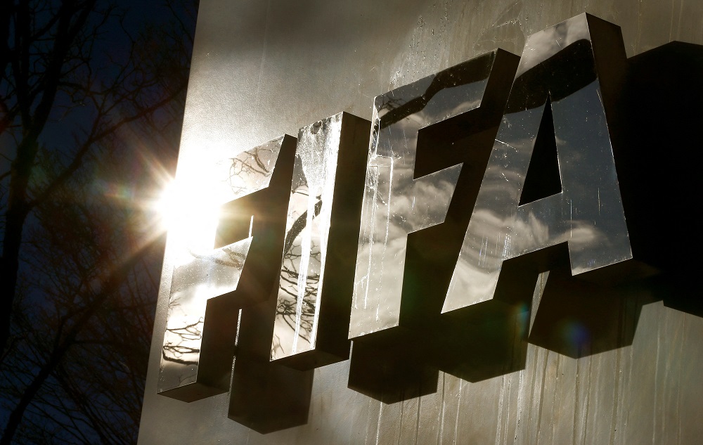FILE PHOTO: The sun is reflected in FIFA’s logo in front of FIFA’s headquarters in Zurich