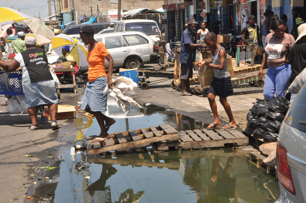 Shoppers often traverse the sewage-stained roads of downtown Kingston with wooden pallets. (Photo: Contributed)