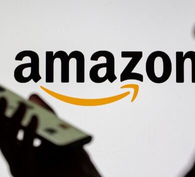 FILE PHOTO: Woman with smartphone is seen in front of displayed Amazon logo in this illustration taken